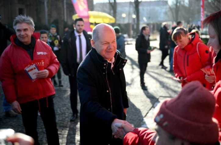 Le chancelier allemand Olaf Scholz (d) rencontre des électeurs alors qu'il fait campagne à Potsdam, la veille des élections législatives, le 22 février 2025 dans l'est de l'Allemagne