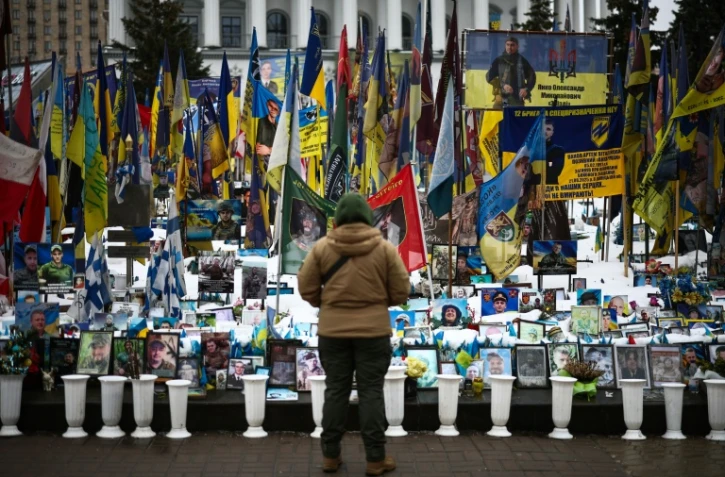 Une personne se tient devant un mémorial de fortune dédié aux soldats ukrainiens et étrangers tombés au combat, sur la place de l’Indépendance à Kiev, le 23 février 2026