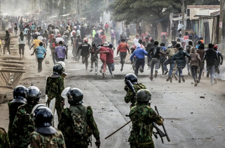 Des manifestants se mettent l'abri lors d'affrontements avec des policiers au cours d'une manifestation contre un centre de quarantaine Ebola construit par les États-Unis sur la base aérienne de Laikipia, le 9 juin 2026 à Nanyuki, au Kenya