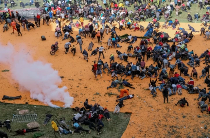 Des partisans et personnes en deuil se mettent à l'abri après que des coups de feu et des gaz lacrymogènes ont été tirés lors d'un rassemblement pour l'exposition publique du cercueil du leader de l'opposition kenyan Raila Odinga au stade Kasarani à Nairobi, le 16 octobre 2025, au lendemain de son décès en Inde