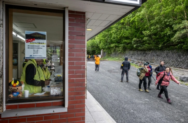 Des randonneurs passent devant le centre administratif de la 5e station de la ligne Fuji Subaru, qui mène au sentier Yoshida pour escalader le mont Fuji, au premier jour de la saison avec les nouvelles mesures de droits d'entrée, le 1er juillet 2024 à Narusawa, au Japon
