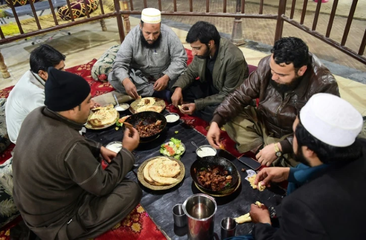 Des Pakistanais dégustent de la viande grillée au restaurant Tikka Nisar Charsi (Tikka "fumeur de haschich" en référence aux habitudes assumées du patron), à Namak Mandi, le coeur gastronomique de Peshawar, le 6 décembre 2018