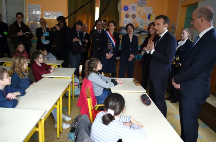 Emmanul Macron (au centre) et le ministre de l'Education nationale Jean-Michel Blanquer (droite) discutent le 15 mars 2018 avec des enfants d'une école prise de Rilly-sur-Vienne dans l'Indre