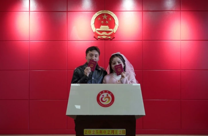 Les jeunes mariés Xue Zhenkai (g) et Liu Cuifang montrent leur livret de mariage dans un bureau de Lüliang, dans la province du Shanxi, dans le nord de la Chine, le 12 février 2025