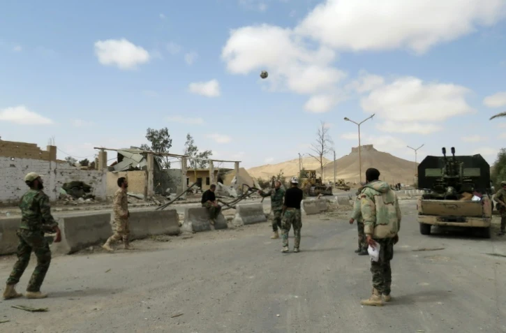 Des soldats syriens jouent au football dans les rues de la cité antique de Palmyre en Syrie, après avoir repris la ville au groupe jihadiste Etat islamique avec le soutien des forces russes, le 27 mars 2016