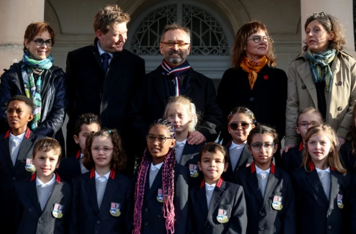 Le maire de Béziers, Robert Ménard (au centre), à côté d'élèves en uniforme dans la cour de l'école primaire du Château de la Chevaliere à Béziers, le 26 février 2024