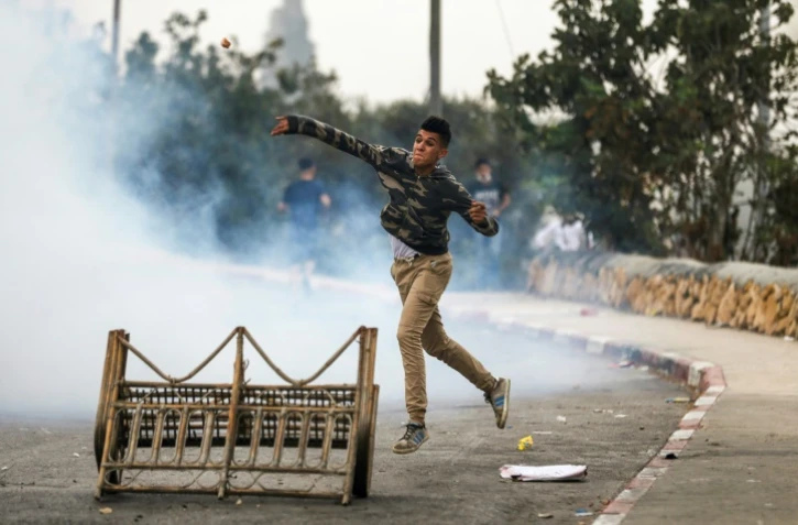 Un manifestant palestinien jette des pierres sur des forces israéliennes lors d'affrontements dans le village de Kobar, à l'ouest de Ramallah en Cisjordanie occupée, le 27 juillet 2018