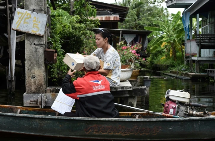 Nopadol, postier, distribue des lettres et colis aux habitants vivant sur les bords d'un canal dans la province de Bang Khun Thian, près de Bangkok en Thaïlande, le 17 juillet 2017