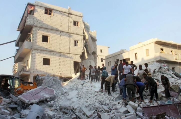 Des habitants et des casques blancs cherchent des survivants le 29 septembre 2017 sous les décombres d'un bâtiment détruit par une frappe aérienne à Harim (nord-ouest) dans la province d'Idlib 