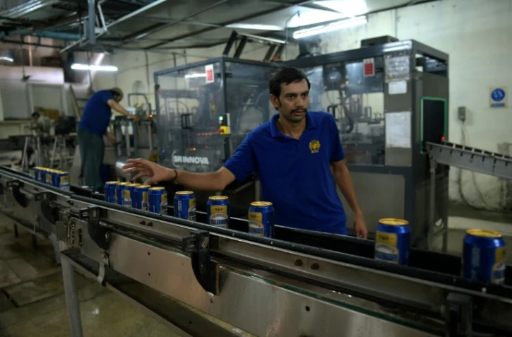 Un salarié pakistanais vérifie une ligne de canettes de bière à la brasserie de Muree à Rawalpindi (province du Pendjab) le 28 juin 2016