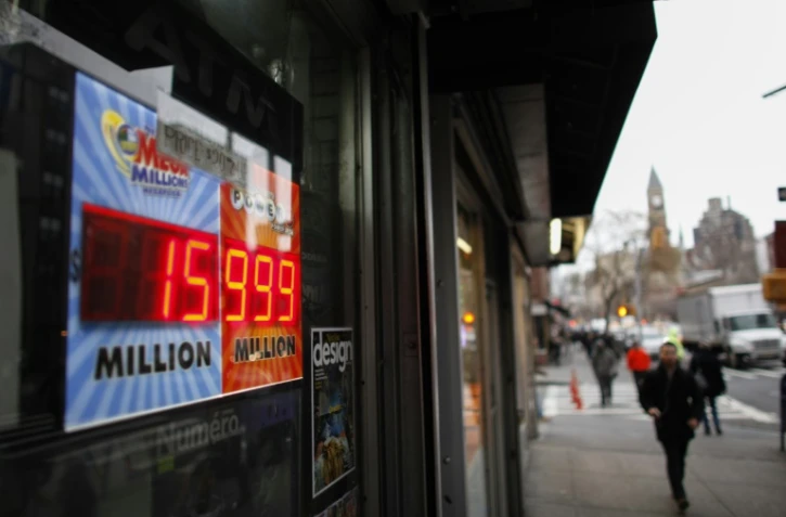 Des gens passent devant un écran de loterie Powerball à New York le 12 janvier 2016