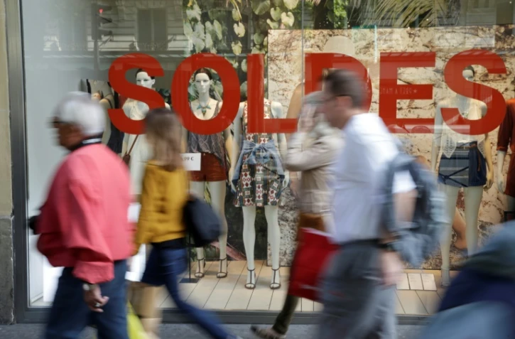 Des passants devant les vitrines des soldes à Paris