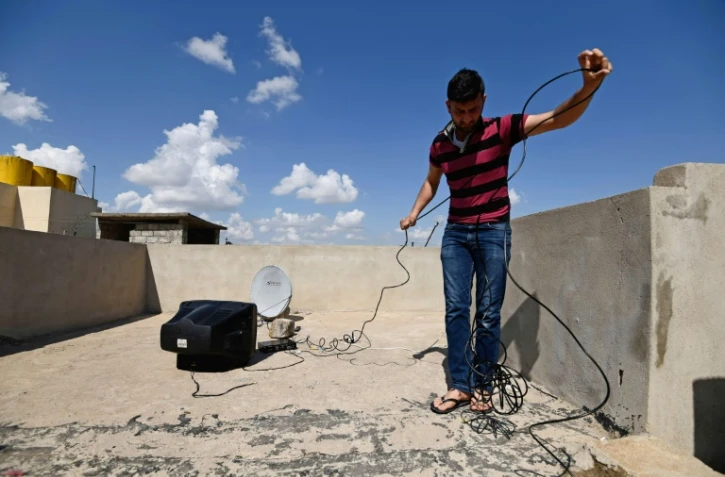 Mohammad Turki installe une parabole sur le toit d'une maison à Mossoul-Est, le 15 avril 2017