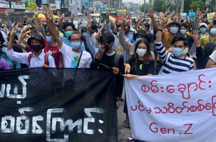 Des manifestants font le salut à trois doigts en défilant contre le coup d'Etat militaire en Birmanie, dans le quartier de Tarmwe à Rangoun le 26 avril 2021