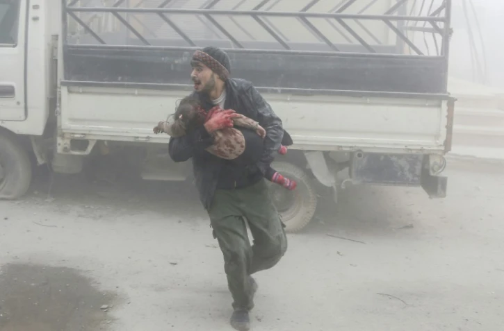 Un Syrien fuit avec un enfant les frappes du régime syrien dans la localité de Saqba, dans la Ghouta orientale, le 6 février 2018
