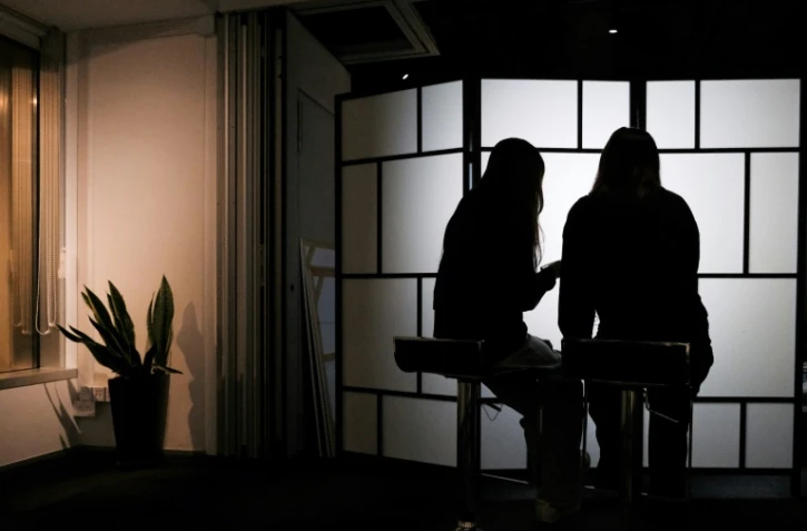Des étudiantes de l'université de Hong Kong victimes de deepfakes pornographiques - B. et C. - regardent leur téléphone, le 29 juillet 2025 à Hong Kong