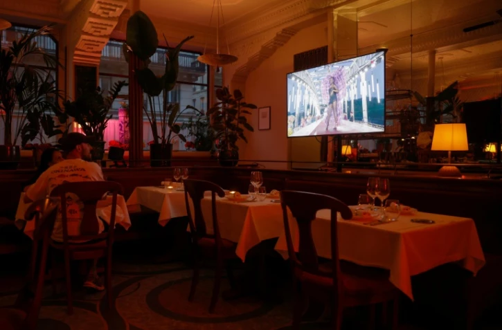 La cérémonie d'ouverture des Jeux olympiques de Paris 2024 passe sur un écran de télévision dans un restaurant à Paris, le 26 juillet 2024