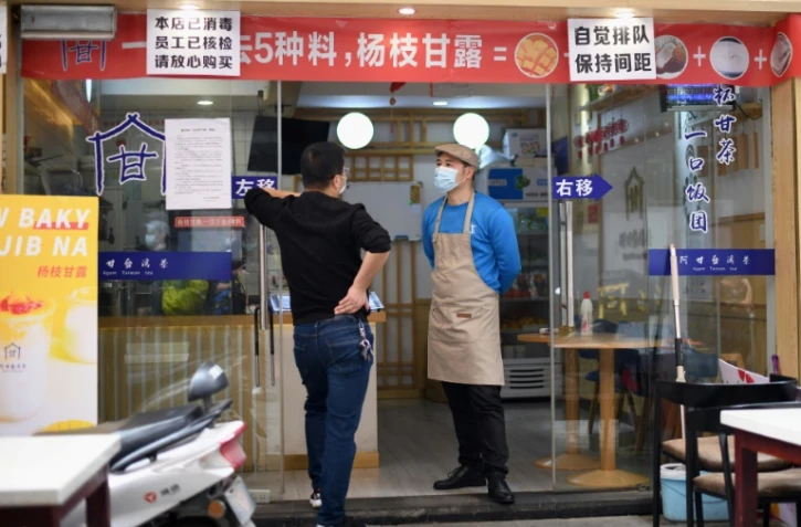 Des employés d'un restaurant munis de masques de protection contre le coronavirus attendent le client à Huanggang, dans la province chinoise du Hubei, le 26 mars 2020 