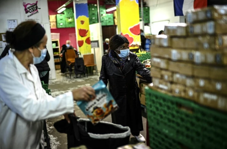 Une bénévole des Restos du coeur distribue une aide alimentaire à des personnes dans le besoin, le 13 octobre 2020 à Paris