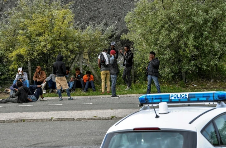 Des policiers face à des migrants sur une route menant à Calais, le 16 août 2017 