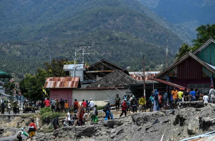 Des habitants marchent le 2 octobre 2018 au milieu des décombres dans le village de Perumnas Balaroa (Indonésie).