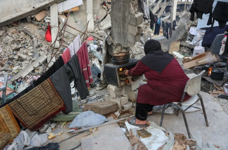 Une Palestinienne prépare un repas sur un poêle de fortune au milieu des décombres d'un bâtiment, le 9 mars 2025 dans le nord de la bande de Gaza