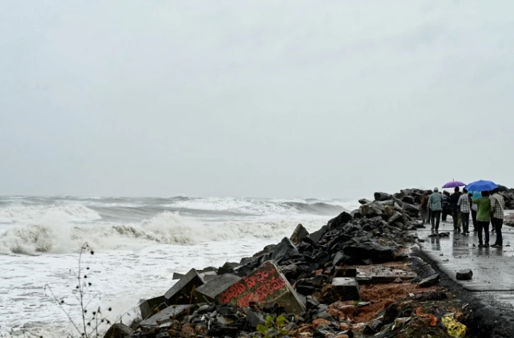Des passants le long de la côte du golfe du Bengale, à Kakinada, en Inde, le 27 octobre 2026, avant le passage attendu du cyclone Arnab