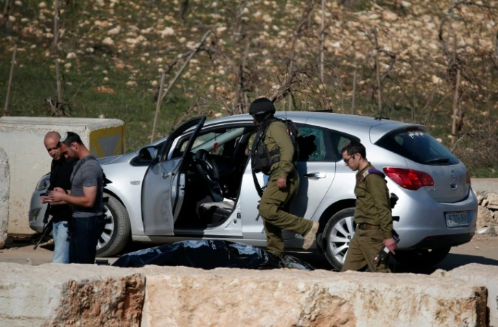 Des soldats israéliens contrôlent le 11 décembre 2015 la voiture d'un Palestinien, abattu dans une tentative d'attaque anti-israélienne à la voiture-bélier au check-point de Halhul, au nord de Hébron, en Cisjordanie