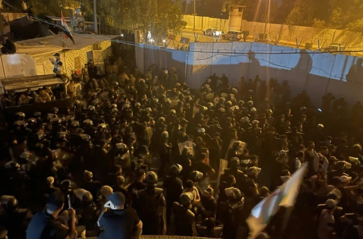 Des manifestants assis sur le toit d'un bâtiment situé à côté de l'ambassade de Suède à Bagdad, le 20 juillet 2023