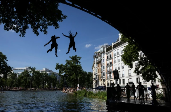 Des jeunes sautent d'un pont dans le canal Saint-Martin lors d'une vague de chaleur Ă Paris, le 22 juin 2026