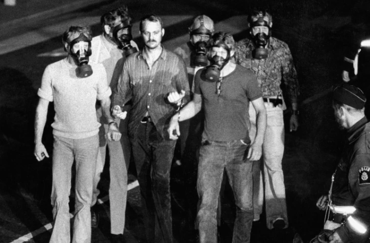Cinq policiers emmènent le braqueur Jan-Erik Olsson à la fin de la prise d'otages de 6 jours à Stockholm le 28 août 1973