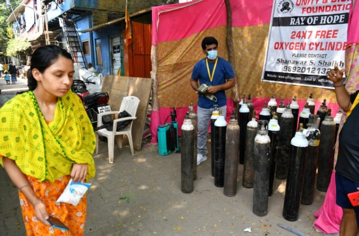 Shanawaz Shaikh (c) fournit gratuitement de l'oxygène pour les personnes atteintes du Covid-19, le 28 avril 2021 dans les bidonvilles de Bombay, en Inde
