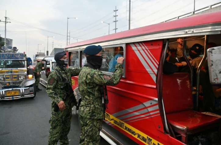 Un policier philippin inspecte un bus à Manille, le 15 mars 2020