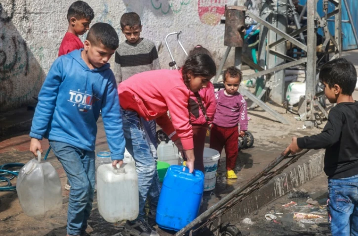 Des enfants s'approvisionnent en eau le 30 mars 2024 à Rafah, dans le sud de la bande de Gaza, où une guerre oppose Israël au mouvement islamiste palestinien Hamas