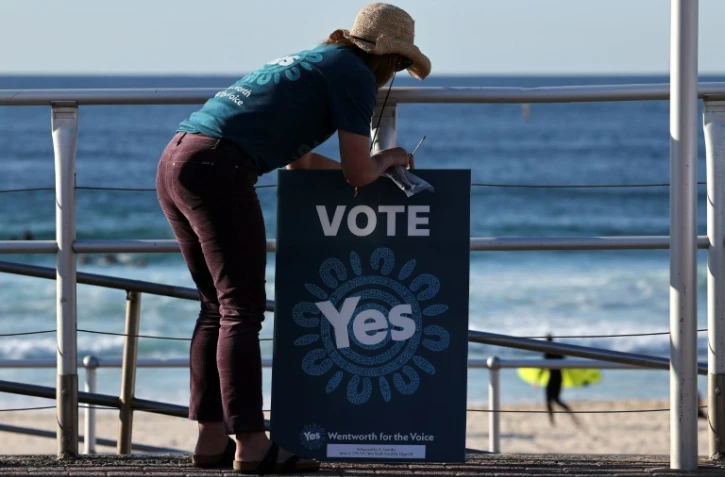 Un volontaire tient une pancarte devant un bureau de vote à Bondi Beach à Sydney le 14 octobre 2023