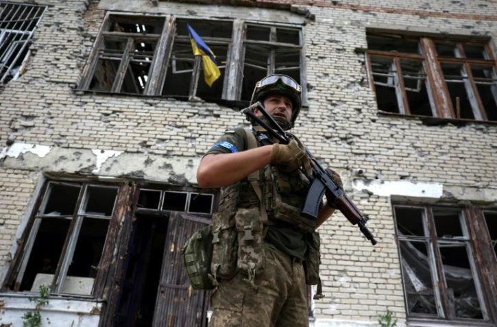 Un soldat ukrainien devant le centre culturel endommagé de Blagodatné, récemment libéré, où flotte le drapeau ukrainien, le 16 juin 2023 dans la région de Donetsk