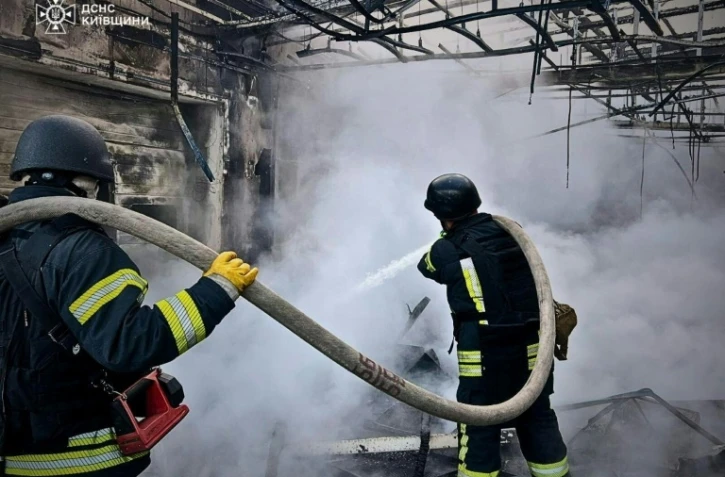 Photo diffusée par le service d'urgence de l'État ukrainien, le 18 mai 2025, de sauveteurs éteignant un incendie dans un bâtiment à la suite d'attaques de drones russes sur la région de Kiev