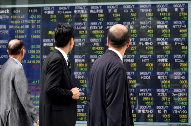Des passants regardent un écran montrant des données boursières à Tokyo, capitale du Japon, le 24 juin 2016