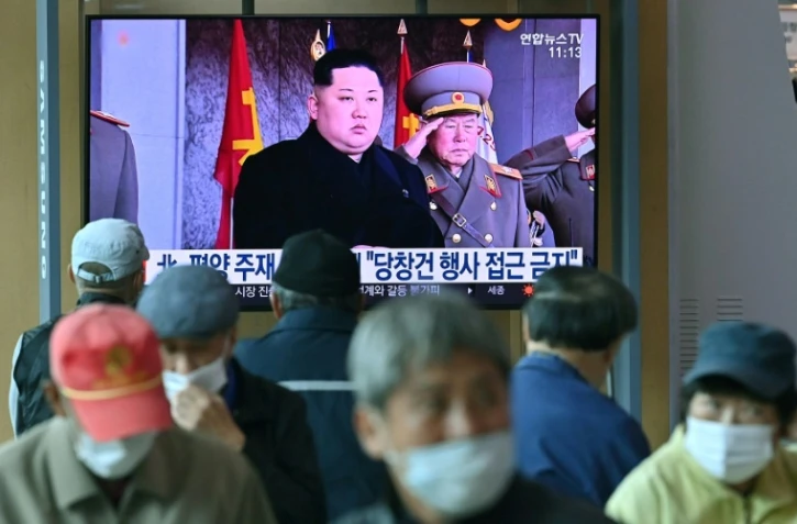 Des passants regardent la télévison qui diffuse des images d'archives du leader nord-coréen Kim Jong Un dans une gare de Séoul le 10 octobre 2020