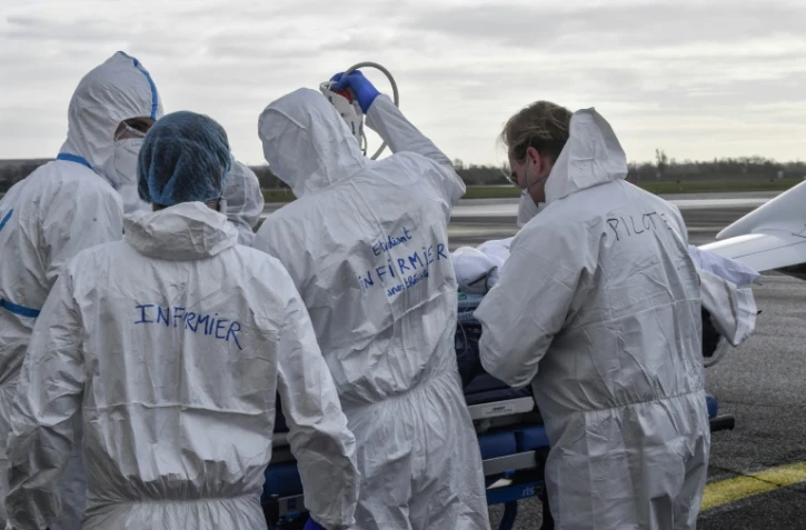 Une équipe médicale entoure un brancard occupé par un malade du Covid-19, le 16 novembre 2020 sur le tarmac de l'aéroport de Bron, près de Lyon