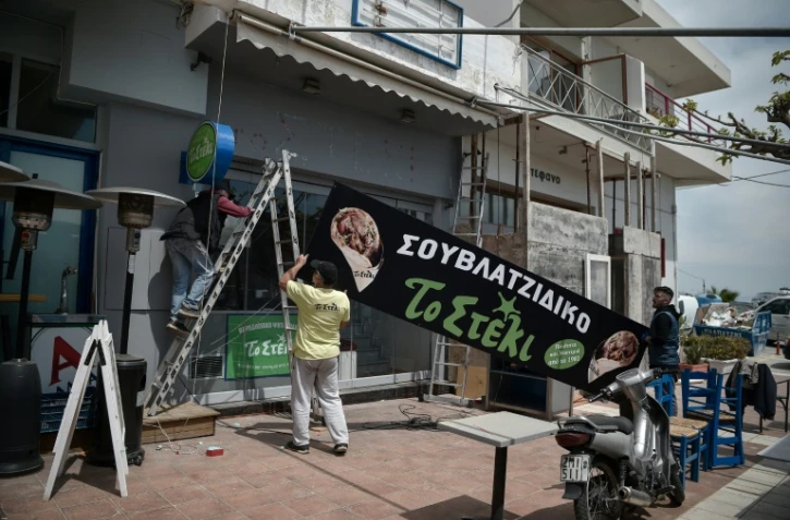 Des employés travaillent à la réouverture d'un restaurant dans le port de Rafina, le 29 avril 2020, près d'Athènes, en Grèce