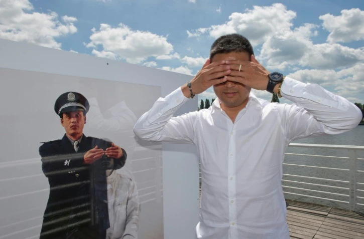 L'artiste chinois Liu Bolin prend la pose devant une de ses oeuvres exposées à Vichy le 16 juin 2017