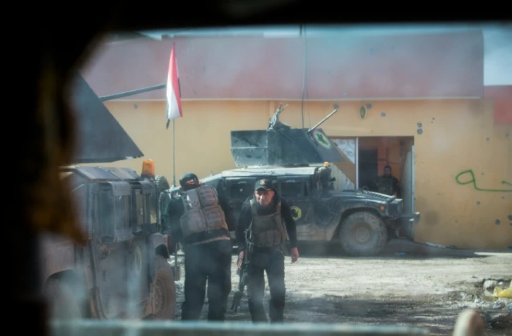 Une photo prise par la fenêtre blindé montre des soldats de la 2ème division des forces spéciales irakiennes se couvrant derrière leurs véhicules sous le feu d'un tireur de l'EI, le 12 novembre 2016, dans le quartier Al-Samah, à l'est de Mossoul