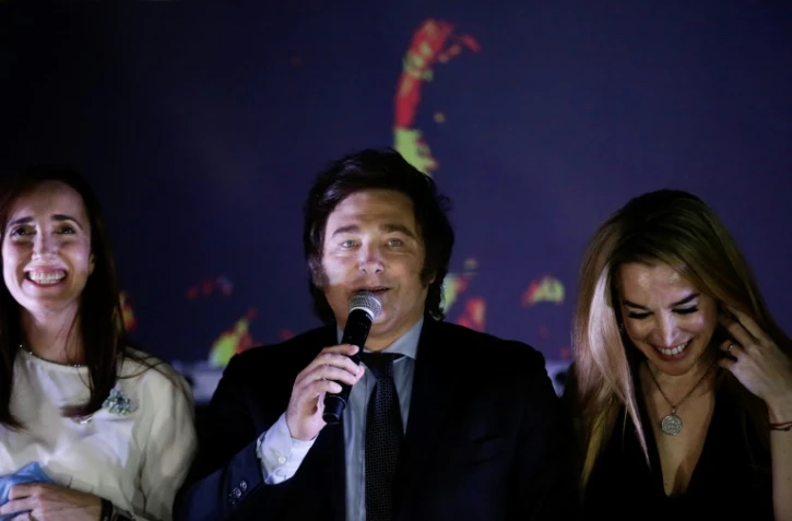 L’économiste ultralibéral Javier Milei (C), vainqueur de la présidentielle en Argentine, s'adresse à ses partisans à Buenos Aires le 19 novembre 2023 aux côtés de sa colistière Victoria Villarruel (G) et de sa compagne Fatima Florez