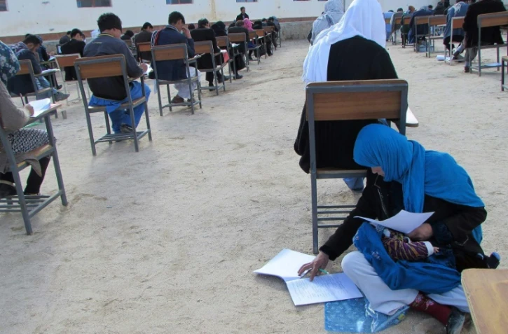 Cette photographie devenue virale en Afghanistan, obtenue depuis le compte Facebook du professeur afghan Yahya Erfan et prise le 16 mars 2018, montre Jahantab Ahmadi passant un examen d'entrée à l'université assise par terre avec son bébé
