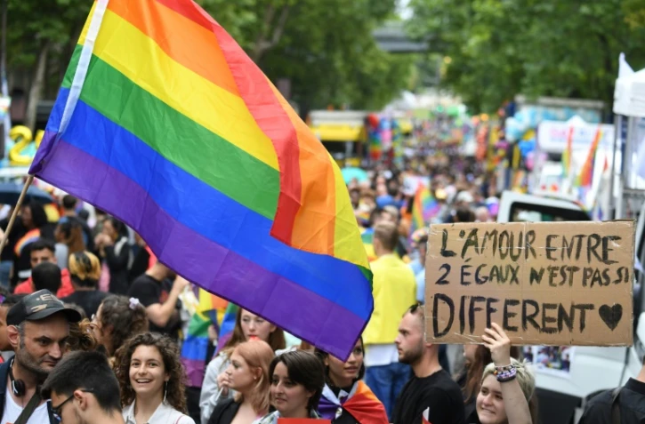 Des participants à la Marche des fiertés à Paris bradissent le drapeau arc en ciel et des pancartes, le 25 juin 2022