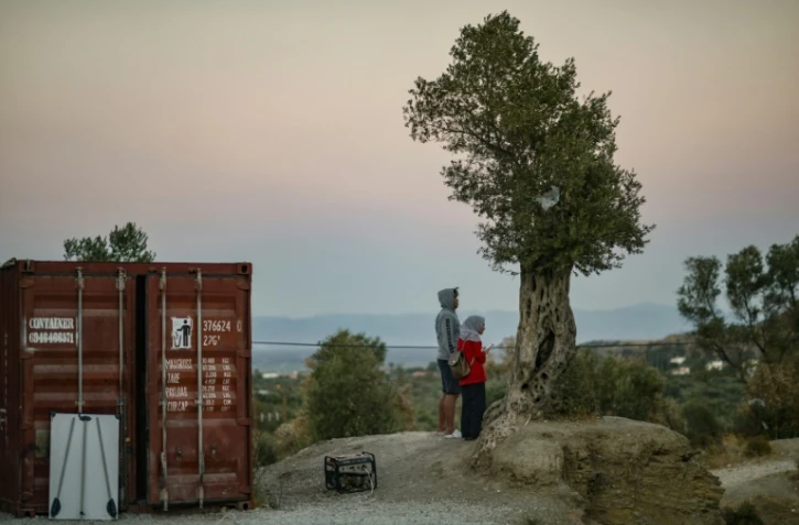 Deux migrants patientent aux abords du camps de Moria, sur l'île de Lesbos, en Grèce, le 25 septembre 2018