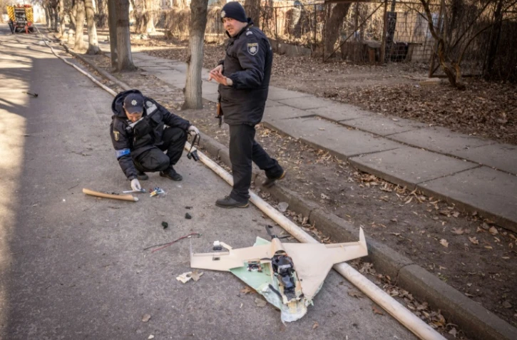 Des policiers ukrainiens inspectent un drone russe abattu dans les environs de l'Académie nationale des sciences, touchée par une frappe, à Kiev, le 22 mars 2022