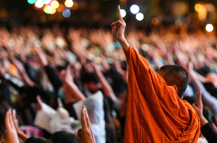 Des manifestants pro-démocratie, dont un moine bouddhiste, lèvent trois doigts en signe de résistance, le 18 octobre 2020 à Bangkok