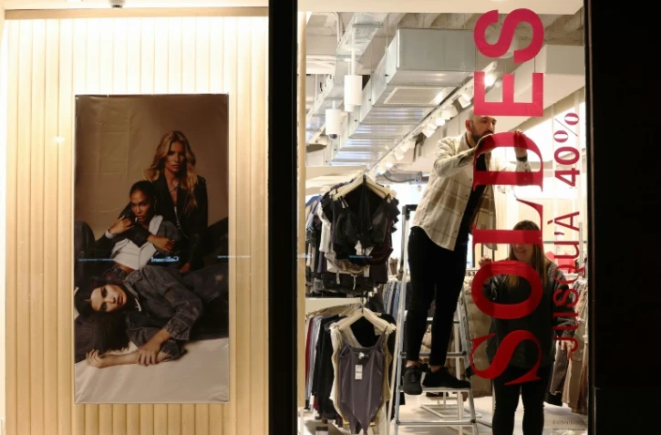 Des commerçants affichent une bannière annonçant les soldes d'hiver la veille de leur lancement le 9 janvier 2024 à Strasbourg